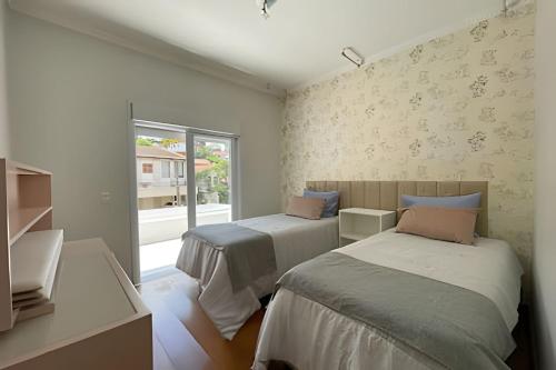 a bedroom with two beds and a window at Mansão com Piscina | Conforto e Exclusividade in Cotia