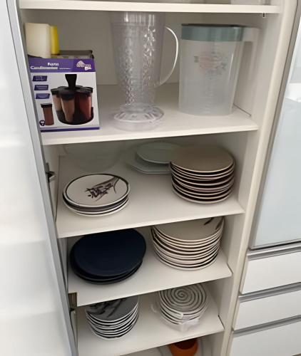 a refrigerator with plates and dishes on shelves at Mansão com Piscina | Conforto e Exclusividade in Cotia
