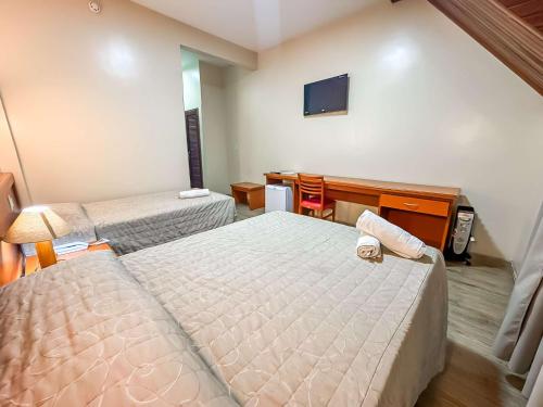 a hotel room with two beds and a television at Hotel Nacional Inn Campos do Jordão in Campos do Jordão