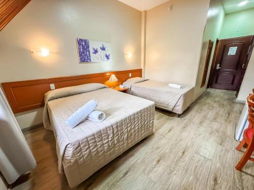 a hotel room with two beds and a table at Hotel Nacional Inn Campos do Jordão in Campos do Jordão