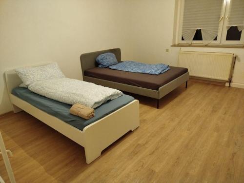 two beds in a room with wood floors at Spacious Flat with 3 bedooms for 5-8 guests in Zeitz