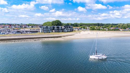 a sailboat in the water next to a beach at Vakantiewoning aan het water - met 4 balkons - Vista Maris - Nr 30 in Sint Annaland
