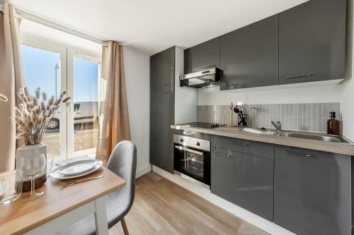 a kitchen with black cabinets and a table and a sink at Bord de l'eau 2 - Studio - Sea view in Cancale