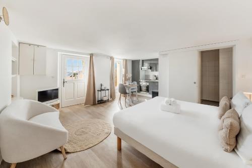 a white room with a white bed and a chair at Bord de l'eau 2 - Studio - Sea view in Cancale