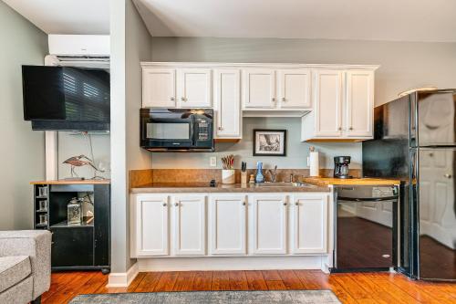 a kitchen with white cabinets and a black refrigerator at Steps to Smith Mountain Lake Unit with Pool Access! in Huddleston