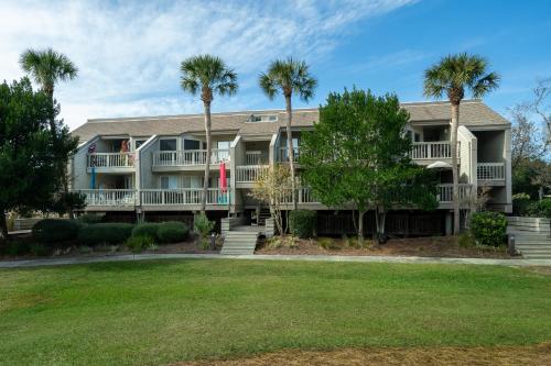 a large apartment building with palm trees at 1644 Courtside Villa in Seabrook Island