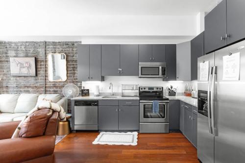a kitchen with stainless steel appliances and a couch at Lush Savannah Loft - Near Plant Riverside District in Savannah