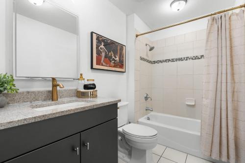 a bathroom with a sink and a toilet and a tub at Lush Savannah Loft - Near Plant Riverside District in Savannah