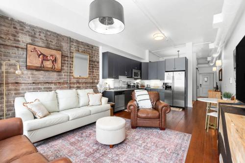 a living room with a white couch and a kitchen at Lush Savannah Loft - Near Plant Riverside District in Savannah