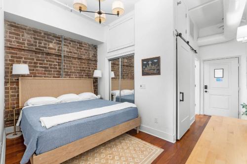 a bedroom with a bed and a brick wall at Lush Savannah Loft - Near Plant Riverside District in Savannah