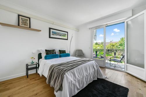 une chambre blanche avec un lit et un balcon dans l'établissement La belle escale entre Paris et Disney, à Le Perreux-Sur-Marne
