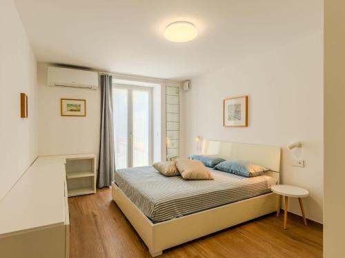 a white bedroom with a bed and a window at Apartment Persico by Interhome in Consiglio di Rumo
