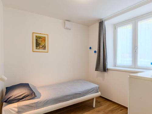 a small bedroom with a bed and a window at Apartment Persico by Interhome in Consiglio di Rumo