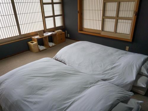 a large white bed in a room with windows at Temple Hotel Takayama Zenkoji in Takayama