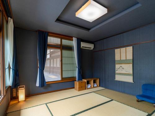 a room with blue walls and a window and a blue chair at Temple Hotel Takayama Zenkoji in Takayama