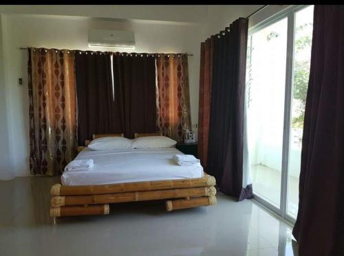 a bed in a room with a large window at Hangout Beach Resort in Caticlan