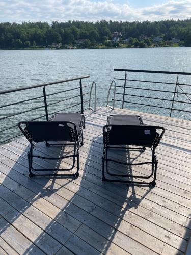 two chairs sitting on a dock near a body of water at Bo på husbåt med egen badplats in Gamleby