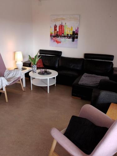 a living room with a black leather couch and tables at Hasselvägen 1 in Hallsberg