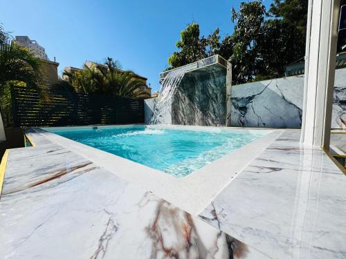 a swimming pool with a waterfall in a backyard at Luxury Villa 6BR with Swimming Pool by Beach - Villa Costa in Rishon LeẔiyyon