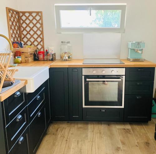 a kitchen with black cabinets and a stove and a window at Maison cosy & chaleureuse - Jardin & Piscine in Hoenheim