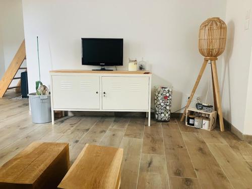 a living room with a tv on a white cabinet at Maison cosy & chaleureuse - Jardin & Piscine in Hoenheim
