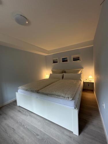 a bedroom with a white bed with two lights on it at Zum Hochufer in Lohme