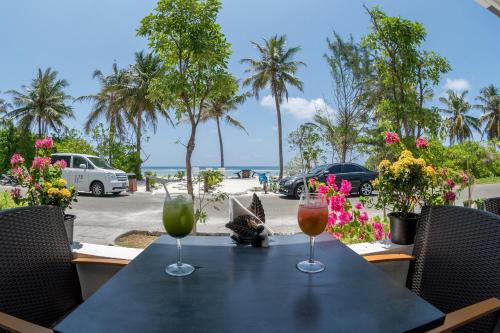 two wine glasses sitting on a table with a view of the beach at h78 in Hulhumale