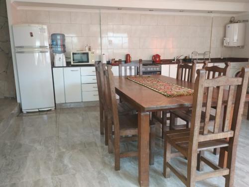 cocina con mesa de madera con sillas y nevera en Lo de matorras 2, en Tandil