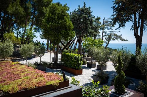 a garden with plants and trees and the ocean at La Ginestra in Fiore Camere in Sirolo