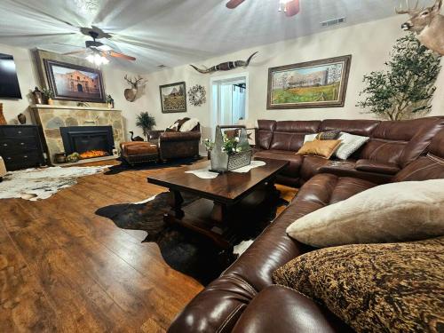 a living room with leather couches and a table at Historic Farmhouse - Tranquil Nature Escape in Hondo