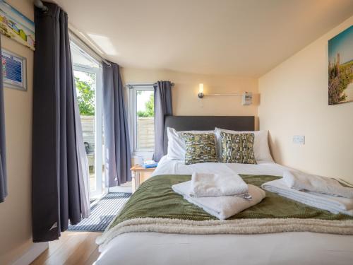 una cama grande en una habitación con ventana en Cosy Cabin for Two with Lovely Countryside Views, Near Kingsbridge, en Churchstow