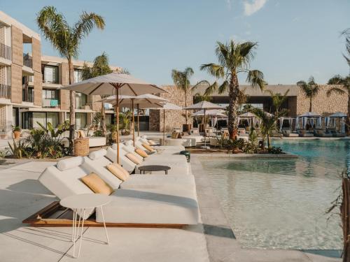 a pool at a resort with white chairs and umbrellas at Bonito Ibiza by O Beach - New Opening 2025 in San Antonio