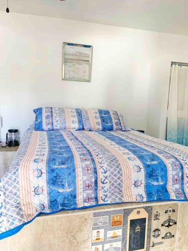 a bed with a blue comforter and pillows on it at Peaceful Beach Studio in the Heart of Puntas in Rincon