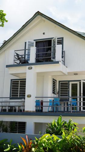 a white house with blue chairs on the balcony at Peaceful Beach Studio in the Heart of Puntas in Rincon