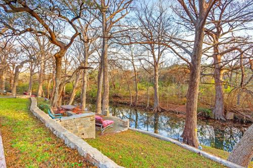 a park with benches and a river with trees at Mill Lodge in Wimberley