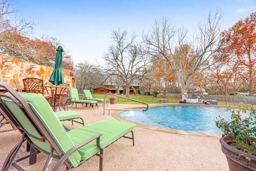 a swimming pool with lawn chairs and an umbrella at Mill Lodge in Wimberley