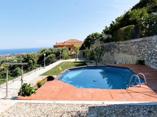 a swimming pool in a garden next to a wall at Borgo Pasqui in Diano Castello
