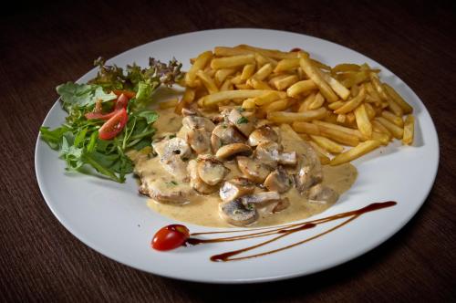 a white plate of food with french fries and sauce at LuCA Hotel in Bodenmais