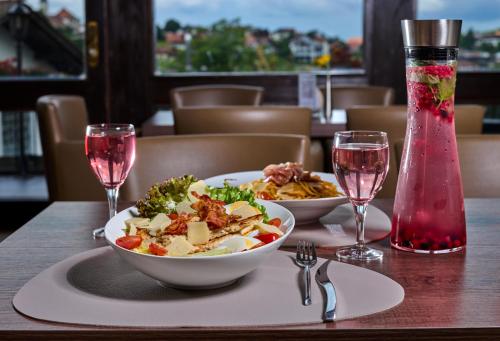 a table with two plates of food and two glasses of wine at LuCA Hotel in Bodenmais