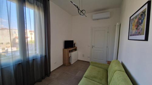 a living room with a green couch and a window at Terrazza sull'Alba in Pisa