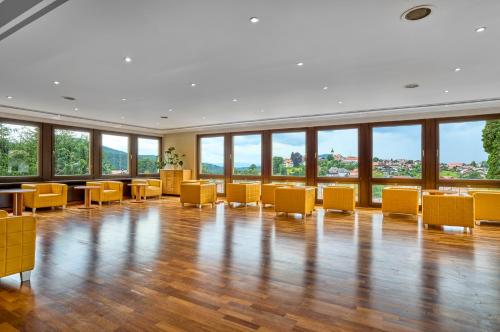 a large room with yellow chairs and tables and windows at LuCA Hotel in Bodenmais