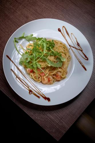 a plate of noodles and greens on a table with chopsticks at LuCA Hotel in Bodenmais