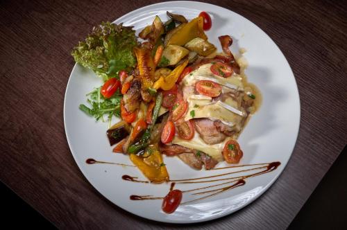 a white plate of food with meat and vegetables at LuCA Hotel in Bodenmais