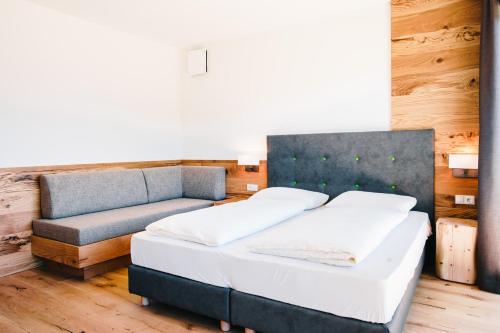 a bedroom with two beds and a couch at Gasthof Hotel Wöhrmaurer in Feldthurns
