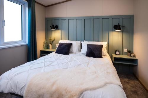 a bedroom with a large white bed with two pillows at Hot Tub Lodge, Victory Liberte 104 in St. Andrews