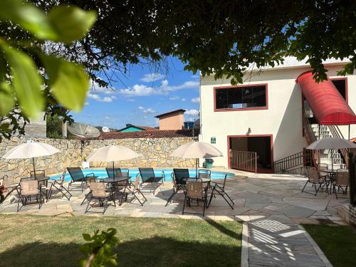 a patio with chairs and umbrellas and a swimming pool at Villa Zen Pirenópolis Conforto e Bem-Estar in Pirenópolis