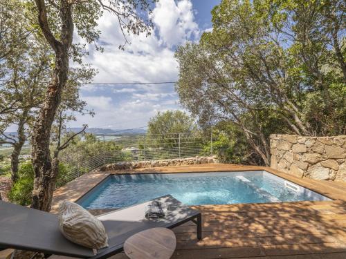 a swimming pool in a yard with a stone wall at Chalet Caseddu D'Arasu by Interhome in Sainte-Lucie de Porto-Vecchio