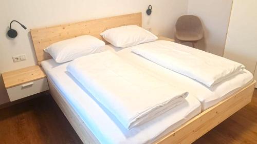 a large bed with white sheets and pillows at Unterdornerhof in Lagundo