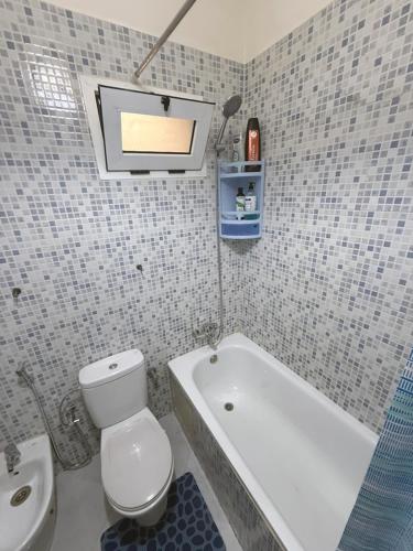 a bathroom with a toilet and a tub and a sink at Charming apartment in marvelous Martil with swimming pool in Martil