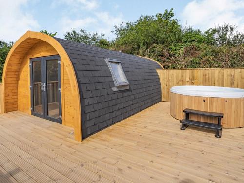 Un pequeño edificio de madera con un jacuzzi en una terraza de madera. en Cwmporthman Farm Cwtch-Uk34700, en Blaenporth